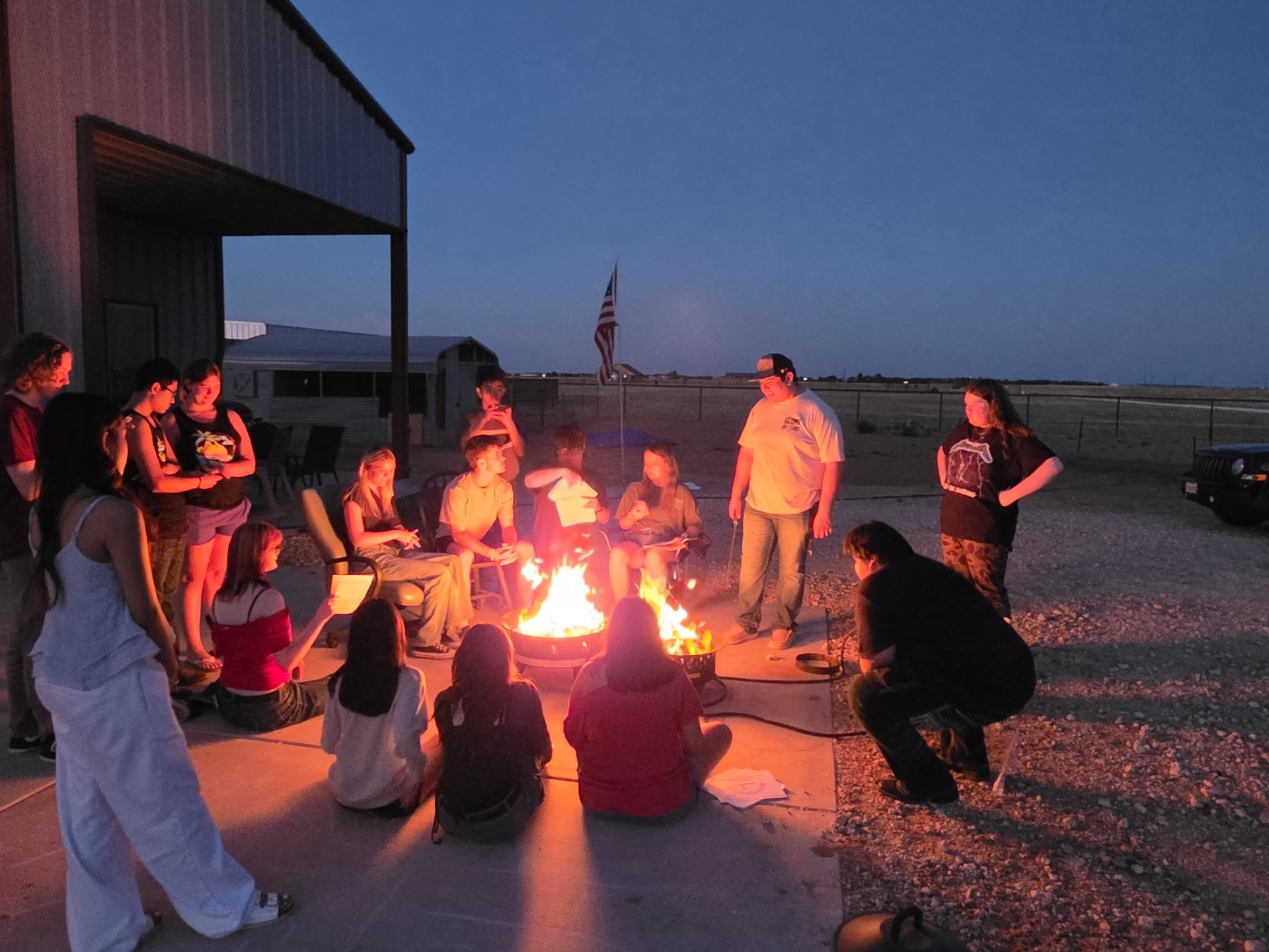 Guests gathered around a fire pit at dusk on the ranch